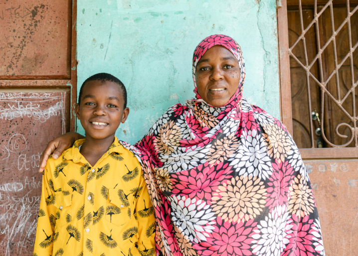 Young boy sits with woman, smiling.